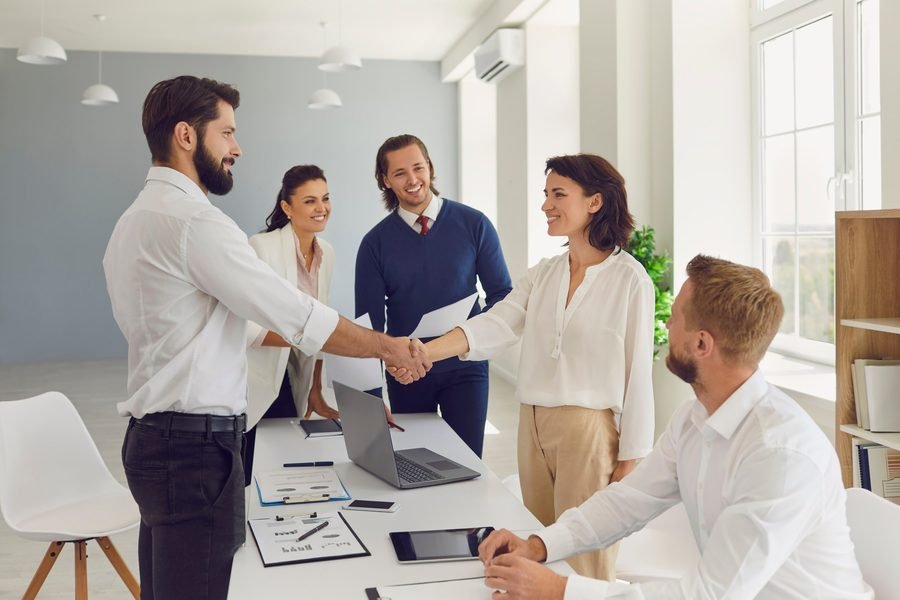 Equipe fechando negócio com aperto de mãos em reunião