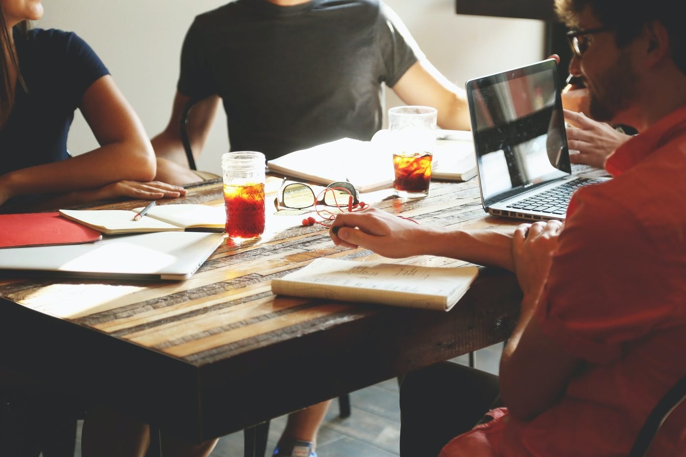 Equipe unindo as mãos ao centro de uma mesa de trabalho